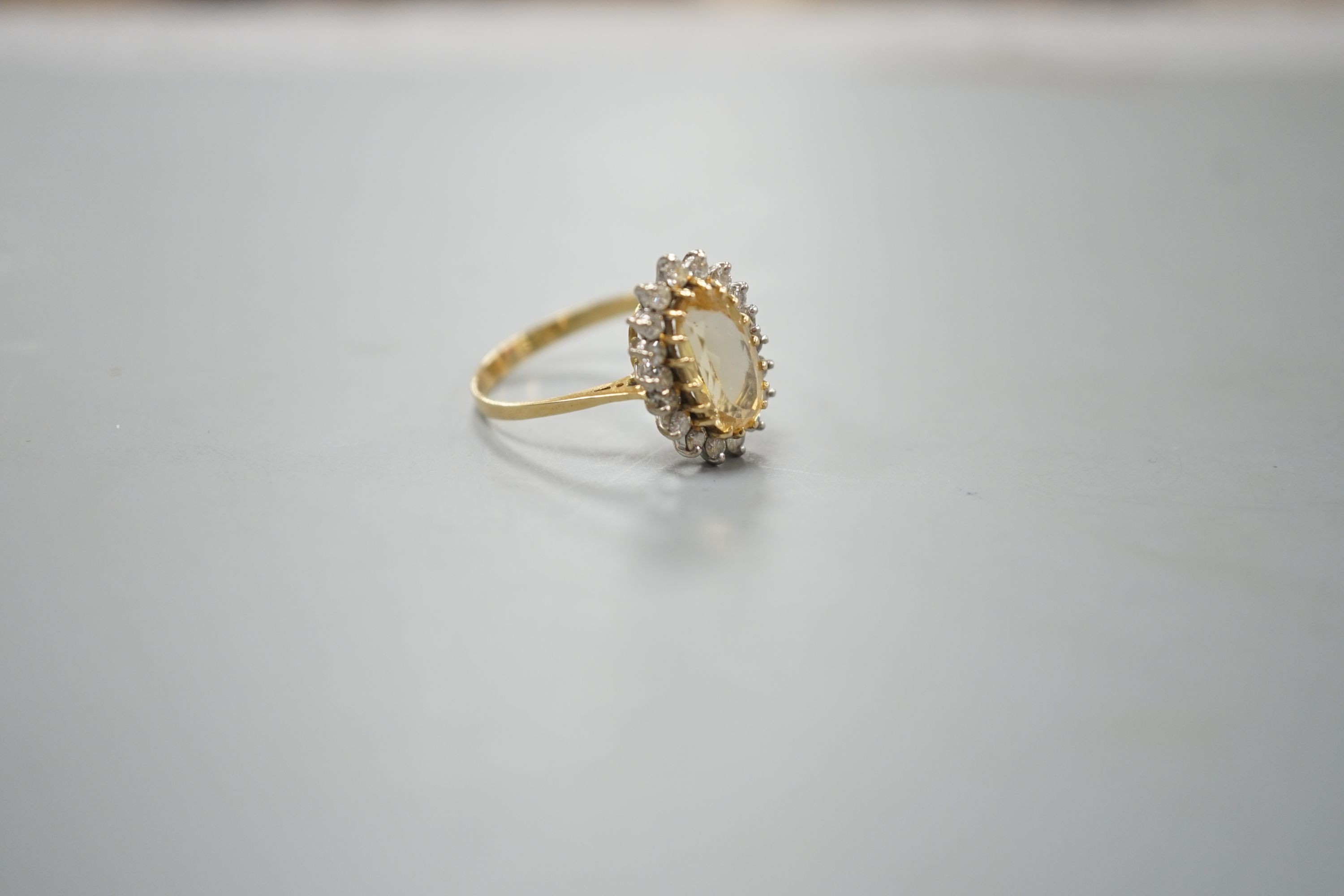 A modern yellow metal, yellow topaz and diamond set oval cluster ring, size T, gross weight 3.7 grams.